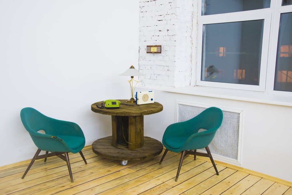 green chair with recycled wooden circle table and phone, lamp, radio on table