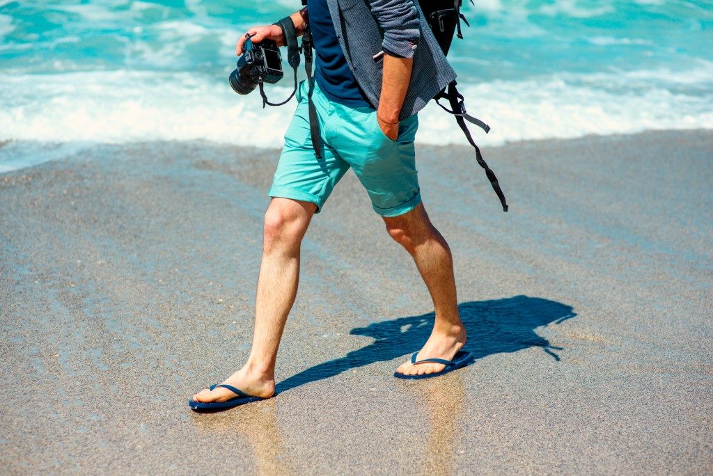 Man holding a camera walking at the beach