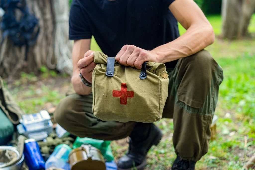 man holding a bag of first aid kit in the camping site