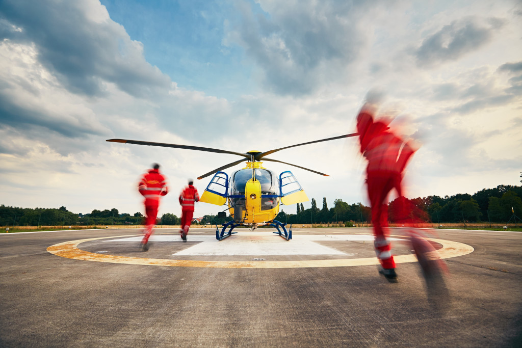 Alarm for the air rescue service. Team of rescuers (paramedic, doctor and pilot) running to the helicopter on the heliport