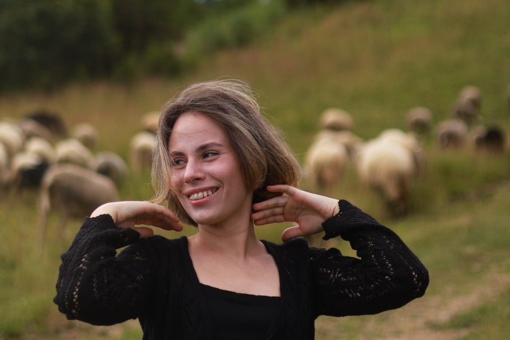 Smiling Woman with Flock of Sheep behind
